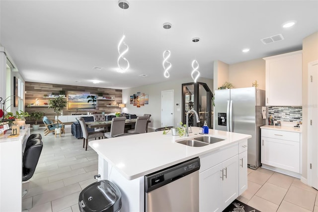 kitchen with backsplash, open floor plan, light countertops, stainless steel appliances, and a sink