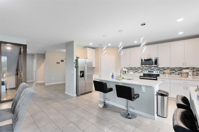 kitchen with tasteful backsplash, light countertops, an island with sink, stainless steel appliances, and a sink