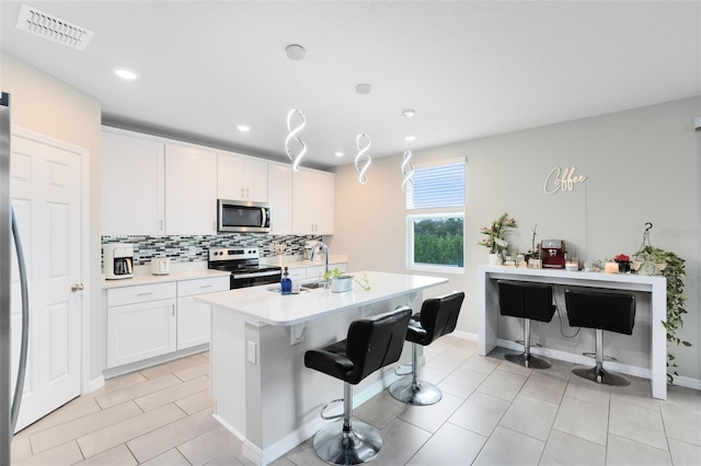 kitchen with visible vents, tasteful backsplash, stainless steel appliances, white cabinets, and light countertops