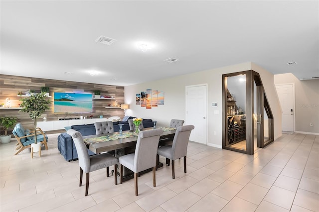 dining area with visible vents, wood walls, and an accent wall