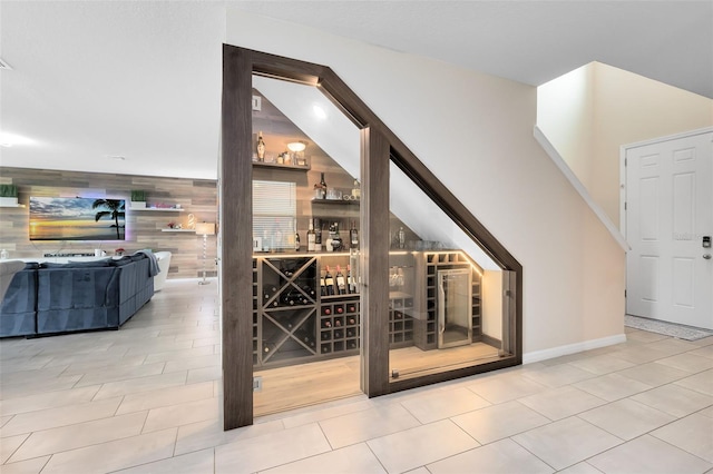 wine area with tile patterned flooring, baseboards, wood walls, and an accent wall