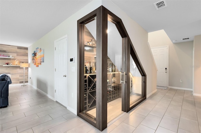 wine room with an accent wall, wooden walls, baseboards, and visible vents