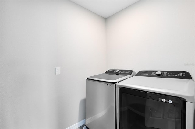 laundry area with laundry area, washing machine and dryer, and baseboards