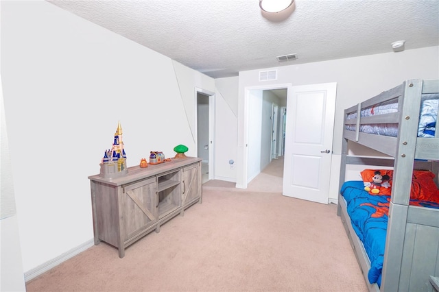 bedroom with light colored carpet, a textured ceiling, and baseboards