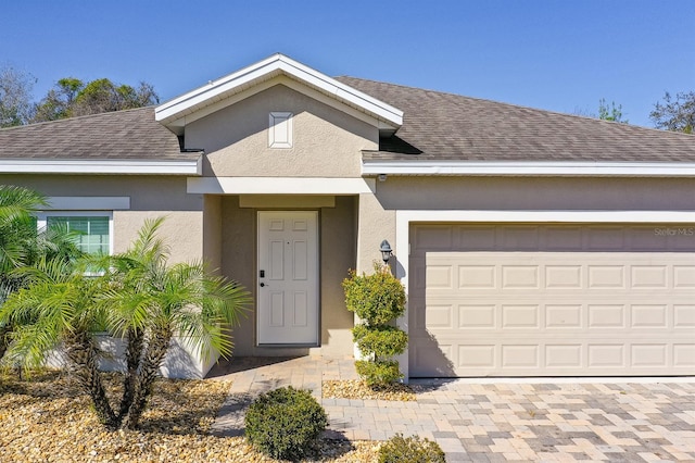 view of front facade with stucco siding, a garage, and roof with shingles