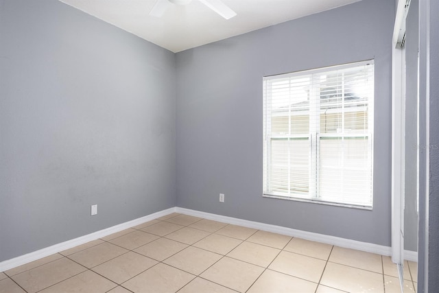 unfurnished room with light tile patterned floors, a ceiling fan, and baseboards