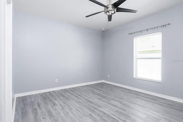 spare room featuring ceiling fan, baseboards, and wood finished floors