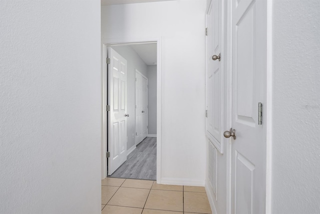 hallway with light tile patterned floors and baseboards