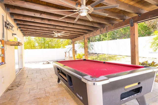 game room with beam ceiling, wood ceiling, a ceiling fan, and stone tile flooring