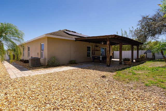 back of property with a patio, central AC unit, fence, stucco siding, and roof mounted solar panels