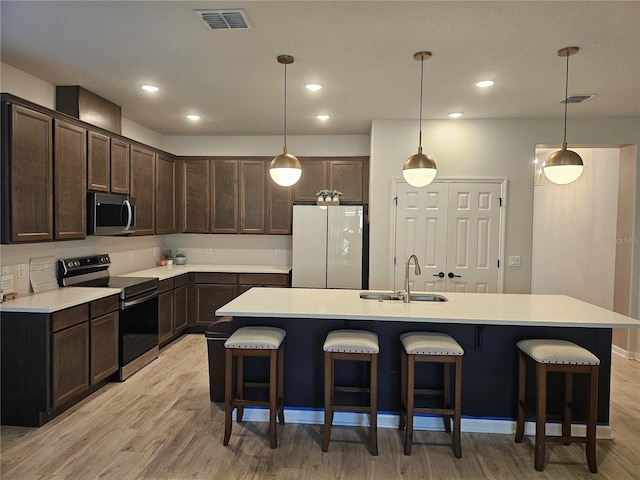 kitchen featuring a kitchen breakfast bar, dark brown cabinets, visible vents, and stainless steel appliances