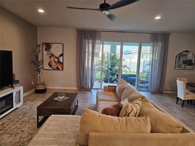 living area with recessed lighting, wood finished floors, baseboards, and ceiling fan