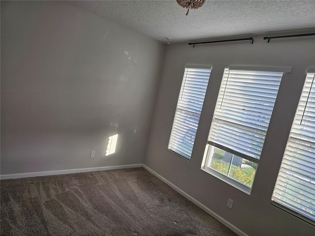 empty room with carpet flooring, a textured ceiling, and baseboards