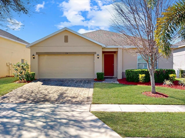 ranch-style home with decorative driveway, an attached garage, a front yard, and stucco siding