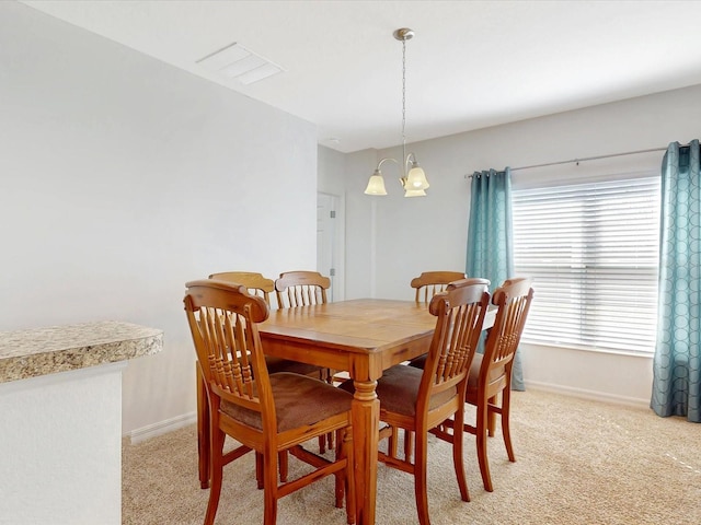 dining area featuring baseboards, a chandelier, and light colored carpet