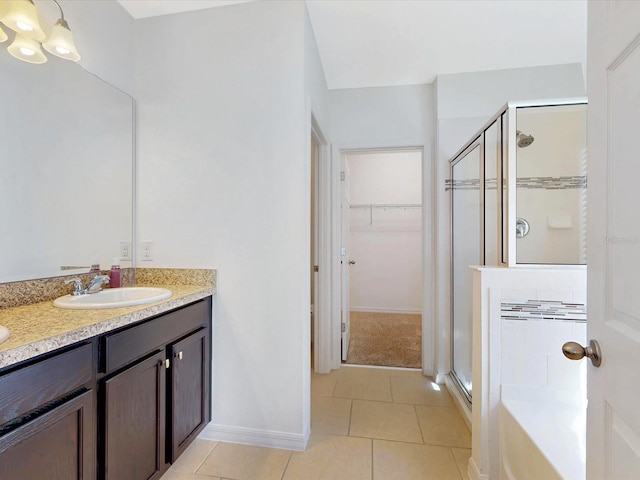 full bath featuring double vanity, tile patterned flooring, a spacious closet, a shower stall, and a sink