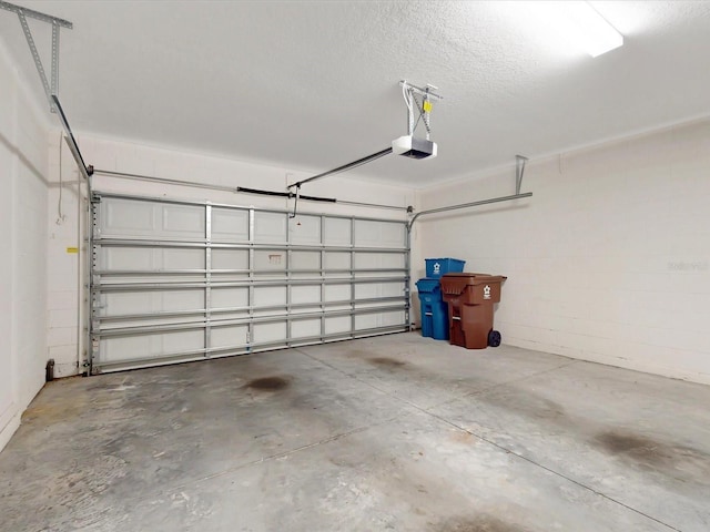 garage with a garage door opener and concrete block wall