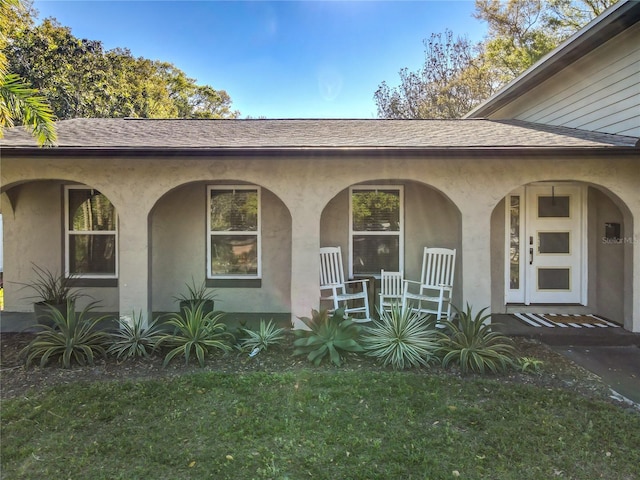 exterior space featuring stucco siding, a porch, and roof with shingles