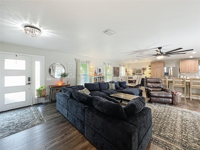 living area featuring visible vents, dark wood finished floors, and a textured ceiling