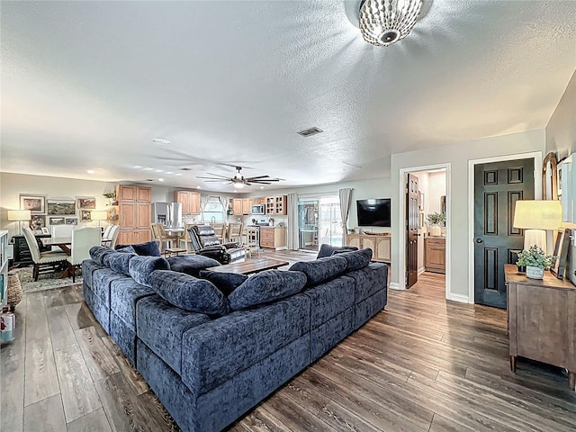 living room with a textured ceiling, dark wood finished floors, and visible vents