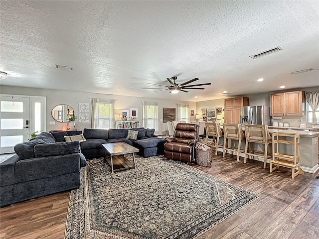 living area featuring recessed lighting, dark wood-style flooring, visible vents, and a textured ceiling