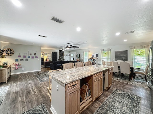 kitchen featuring dark wood-style floors, visible vents, open floor plan, and a kitchen breakfast bar