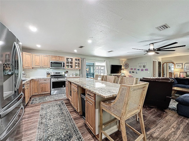 kitchen with open floor plan, visible vents, stainless steel appliances, and a kitchen breakfast bar