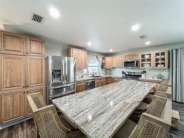 kitchen featuring dark wood finished floors, appliances with stainless steel finishes, a breakfast bar, and visible vents