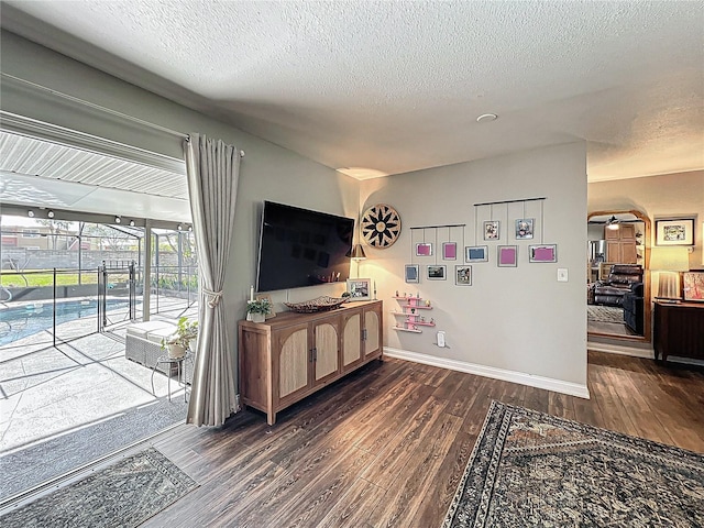 living room featuring ceiling fan, a textured ceiling, baseboards, and wood finished floors