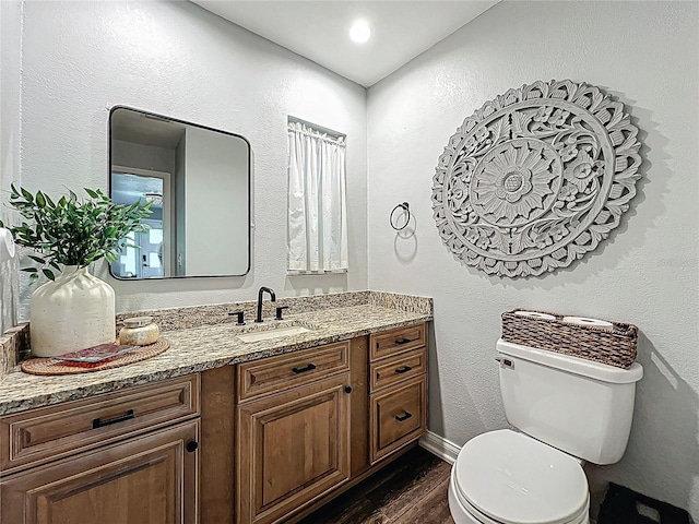 bathroom featuring a textured wall, vanity, toilet, and wood finished floors