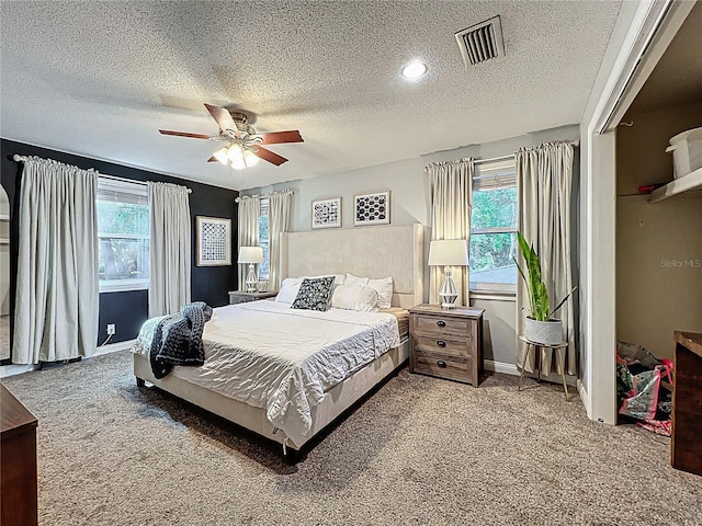 bedroom featuring carpet floors, ceiling fan, visible vents, and a textured ceiling