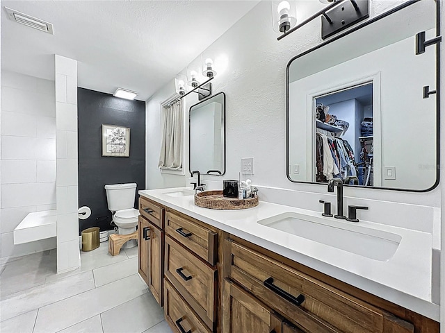 bathroom with toilet, a sink, visible vents, and tile patterned floors