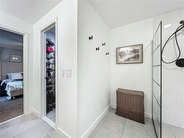 hall featuring light tile patterned floors and baseboards