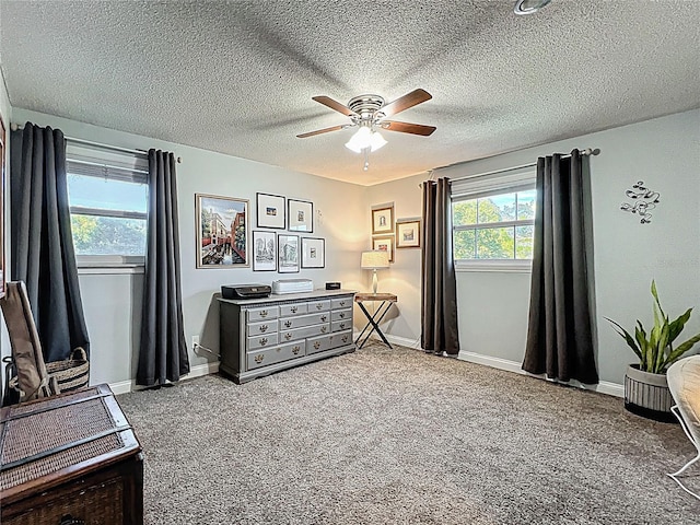 carpeted bedroom with a textured ceiling, a ceiling fan, and baseboards