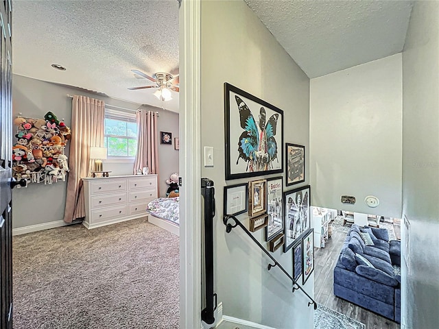 carpeted bedroom featuring a ceiling fan, a textured ceiling, and baseboards