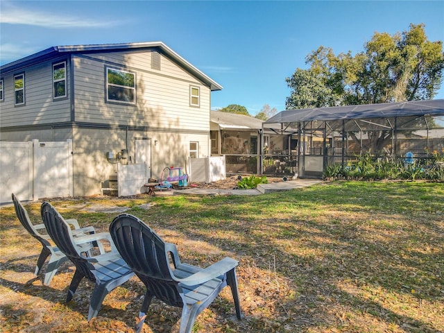 rear view of house featuring a lawn and a lanai