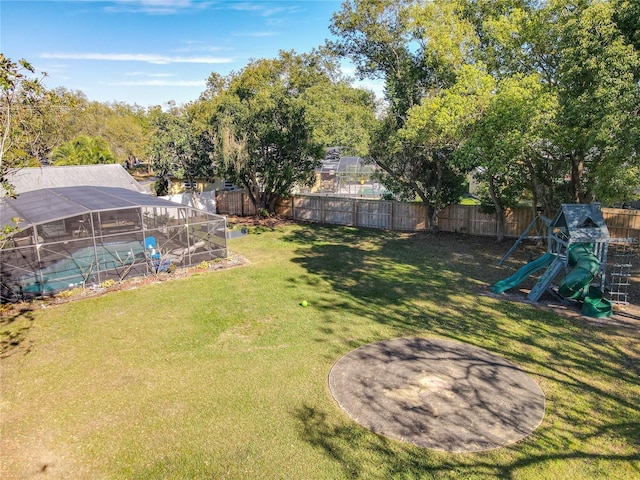 view of yard with glass enclosure, a fenced backyard, and a playground