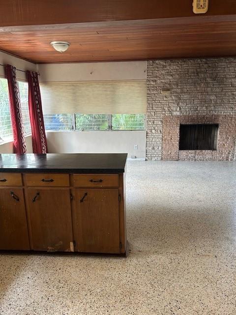 kitchen featuring dark countertops, light speckled floor, a fireplace, and wood ceiling