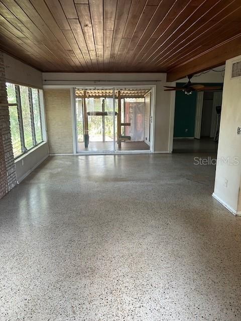 unfurnished room with wood ceiling, speckled floor, and baseboards