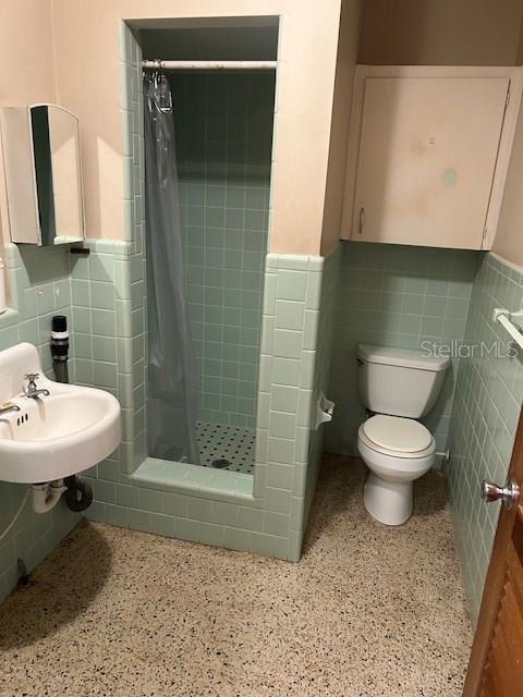 bathroom featuring speckled floor, tile walls, and a wainscoted wall