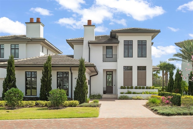 view of front of property with a tiled roof, a chimney, and stucco siding