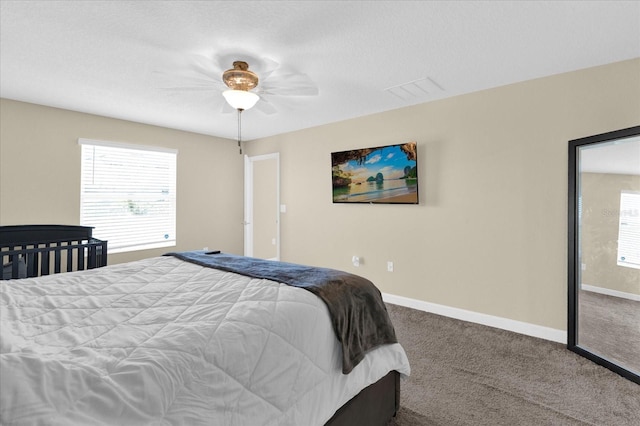 carpeted bedroom with baseboards, multiple windows, visible vents, and a ceiling fan