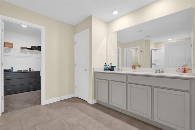 bathroom featuring a sink, baseboards, a stall shower, and double vanity