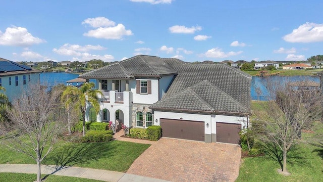 view of front facade featuring a tile roof, a balcony, decorative driveway, and a garage