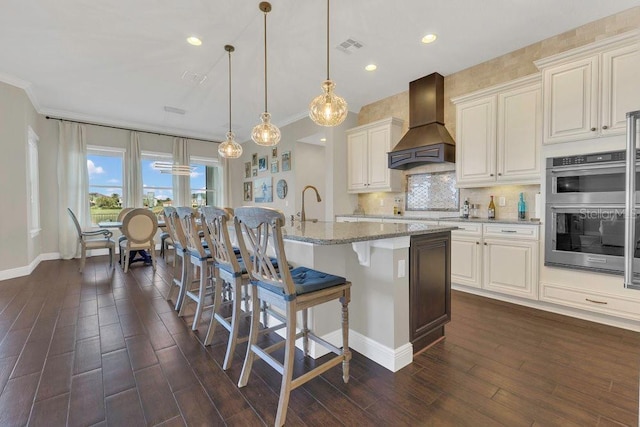 kitchen with backsplash, premium range hood, a kitchen bar, light stone counters, and stainless steel double oven