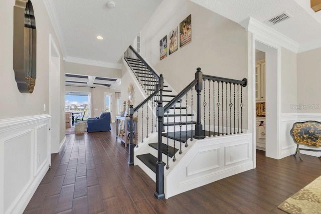 stairs featuring a decorative wall, a wainscoted wall, visible vents, and wood finished floors