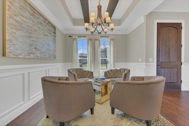 living room featuring wood finished floors, a raised ceiling, a chandelier, and crown molding