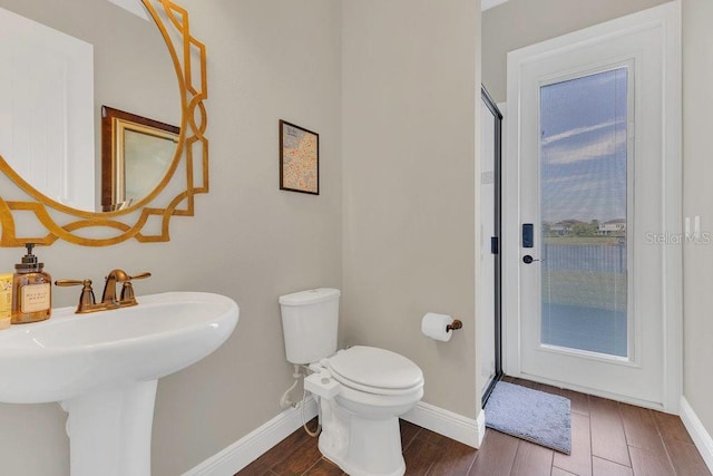 full bathroom with toilet, wood finished floors, baseboards, and a sink