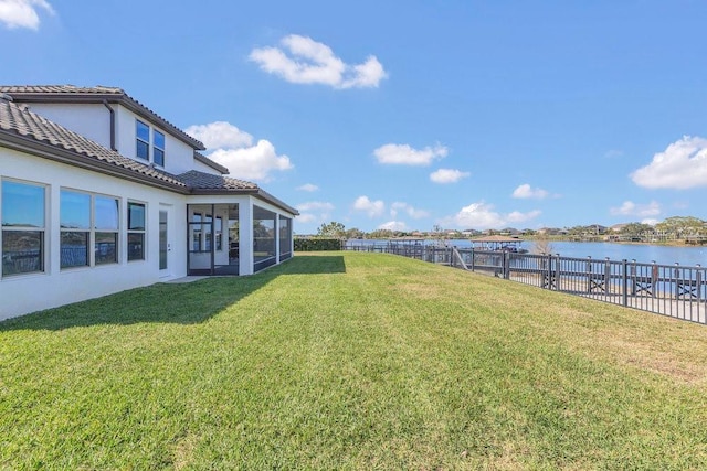 view of yard featuring a sunroom, a fenced backyard, and a water view