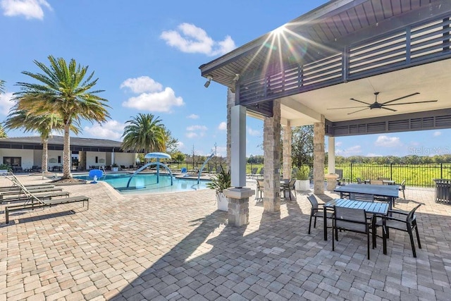 view of patio / terrace featuring a ceiling fan, outdoor dining area, a community pool, and fence